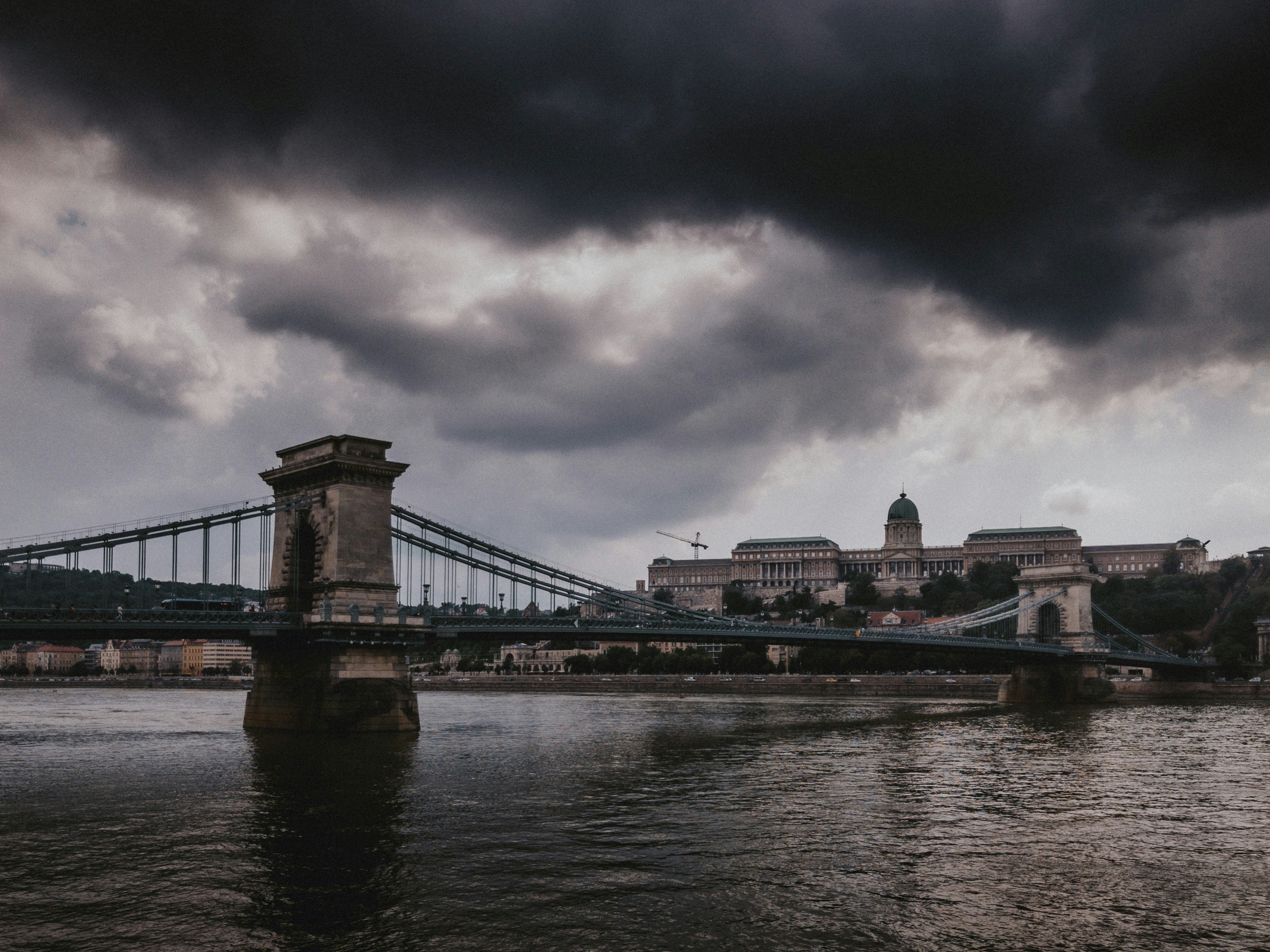 bridge over river under cloudy sky